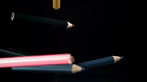 Colorful Pencils Falling on a Shiny Black Surface
