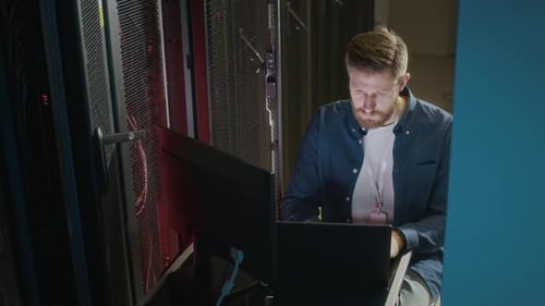 Technician Working on Laptop in Server Room