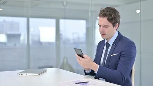 Professional Young Businessman using Smartphone in Modern Office