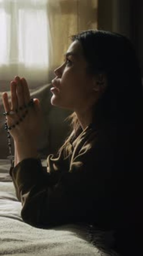 Young Woman Prays with Rosary Beads in Bedroom