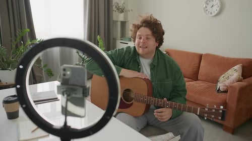 Young Man Playing Guitar Recording Video