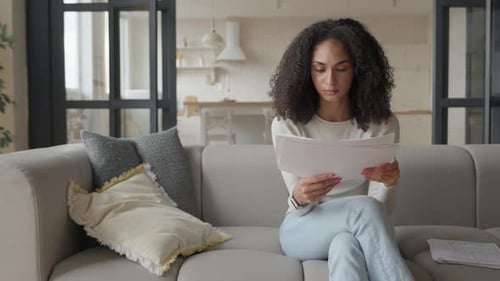 Woman Reviews Documents While Sitting on Couch