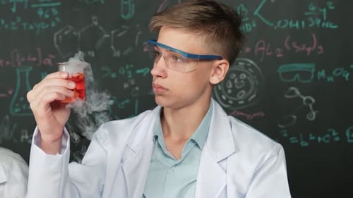 Teenage Boy Examines Smoking Beaker in Science Lab
