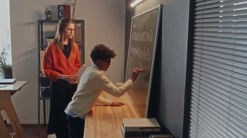 Little Boy Writing Music Notes on Board while Teacher Watching Him