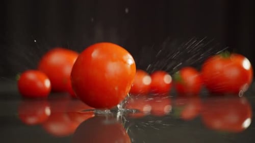 One By One Large Tomatoes Fall Onto the Wet Surface Forming Splashes