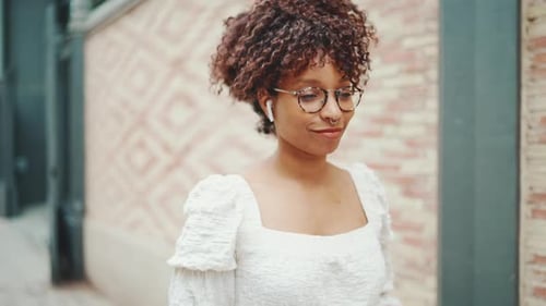 Woman walks along the street and listens to music in wireless headphones