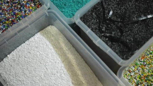 Live Camera Moves Along Boxes with Sorted Plastic Garbage of Different Colors Top View Closeup