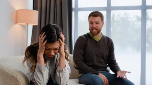 Couple Arguing on Couch Indoors During Daytime