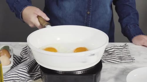 Frying Farm Fresh Eggs in a White Skillet