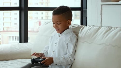Happy Boy Playing Video Game on Couch Indoors