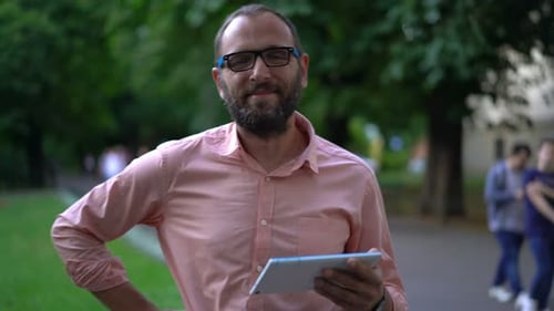 Portrait of Happy, Young Man with Tablet at City Park 30s