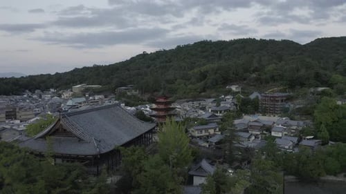 A drone pull back shot of Senjokaku five-story pagoda on Miyajima island, Japan at Sunset