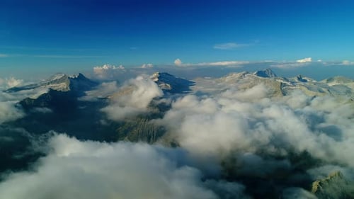Aerial view over the alpine mountain chain. High view of the alps mountain peaks. Picturesque clouds
