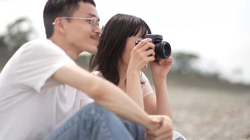 Happy Couple with Camera on Rocky Beach