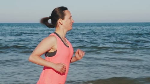 Sporty girl running on beach at sunset