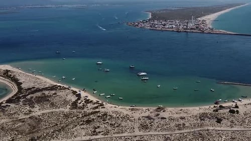 Desert Island Bay, small boats moored on emerald water with LightHouse island in Background, Algarve