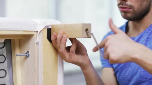 Man assembling new sofa legs in apartment room during home furnishing project