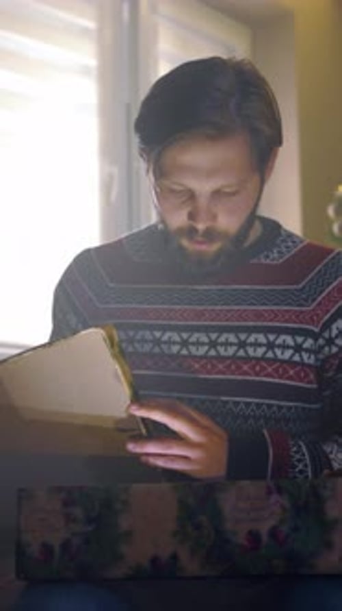 Man with Beard Opens Christmas Present at Home