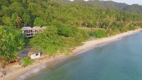 Tropical Island drone backwards dolly shot of beach resort with lush green rain forest and tropical