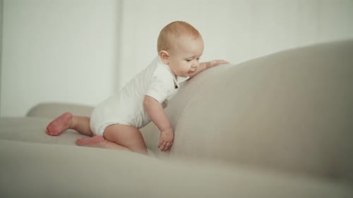 Infant Crawling on Gray Couch in a Light Home