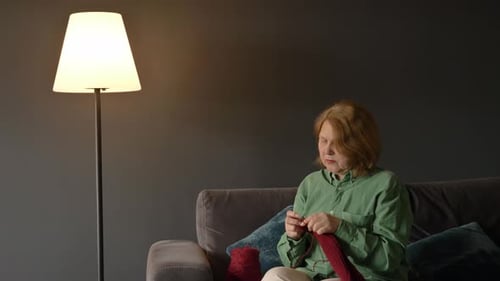 Woman Knitting on Couch with Yarn and Needles