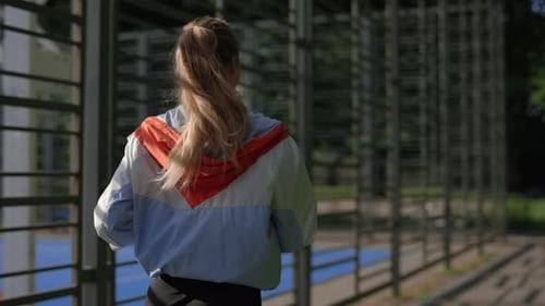 Back View of the Woman Running Near the Sport Field Wearing Special Sport Clothes