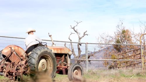 Cowboy Driving Tractor in a Round Pen Arena