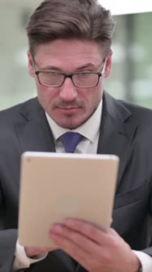 Attractive Middle Aged Businessman Using Digital Tablet, vertical video