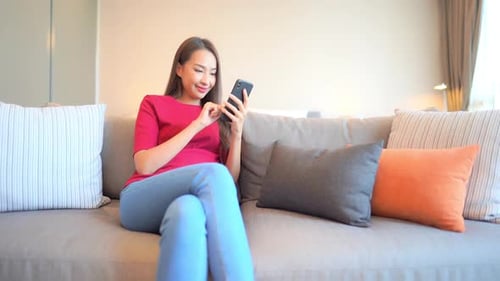 Woman Relaxing on Sofa Using Mobile Phone