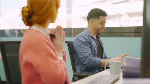 Colegas de trabalho sorrindo enquanto trabalham em conjunto com computadores