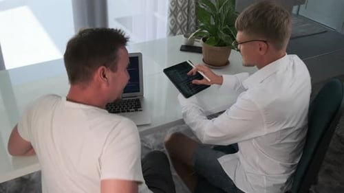 Two Men Collaborate on Code at Modern Desk