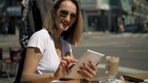 Portrait of Happy, Pretty Woman with Tablet Sitting in Cafe in City 30s