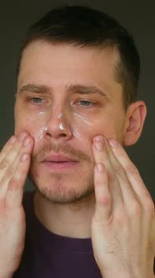 Man Applying Skincare Cream to Face in Close Up
