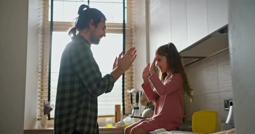 Happy Father a Brunette Man in a Checkered Green Shirt Plays with His Little Brunette Daughter in a