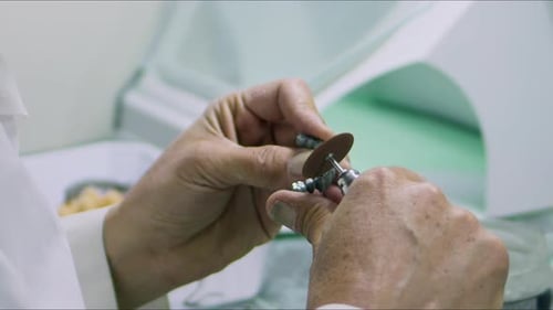 Hands Using Rotary Tool on Dental Mold