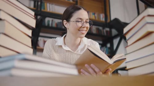 Young Woman Student or Businesswoman Reading a Book in the Library Students in a Good Mood Studying