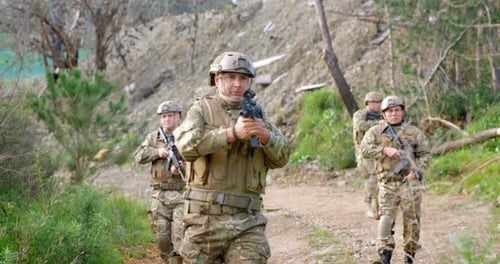 Vue de face de soldats militaires biraciaux s'entraînant au fusil dans les champs pendant l'entraînement militaire 4k