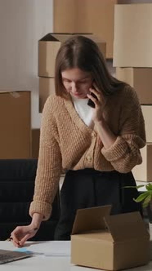 Woman Taking Notes While Talking on Phone in Office