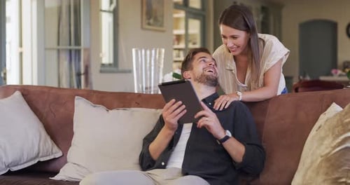 4k video footage of a happy young couple using a digital tablet on the sofa at home
