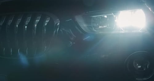 Close up of details of switched on headlights of anonymous prestigious luxury modern car. Shot in