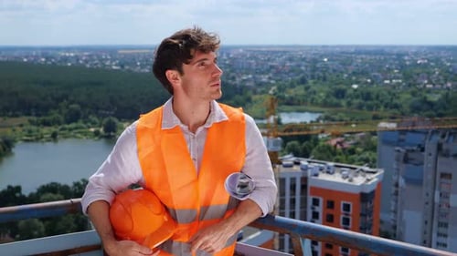 Construction Worker on Rooftop Overlooking Urban Landscape