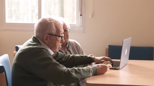 Happy Elderly Man and Woman Using Laptop and Credit Card at Nursing Home