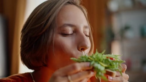 Young Woman Enjoys Healthy Sandwich in Sunny Kitchen