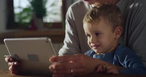 Happy Child with Woman Looking at Tablet