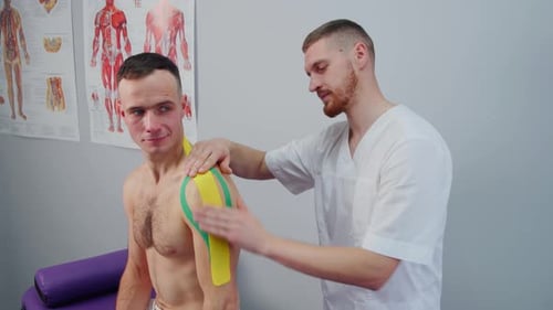Applying Kinesiology Tape to Man's Shoulder