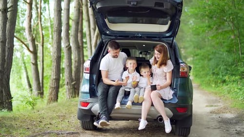 Family Relaxing in SUV Trunk in Forest