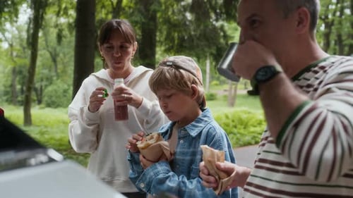 Family Picnic Enjoying Lunch in Green Urban Park
