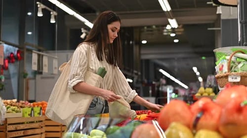 Mujer recogiendo pimientos en una bolsa reutilizable en una tienda. Temáticas del Día de la Tierra y la Ecología. Cámara lenta