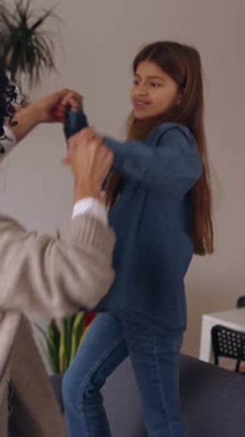 Young Latin Mother Having Fun with Her Daughter Dancing on the Sofa at Home