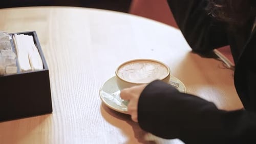 Caucasian Woman Drinking Cappuccino Inside of Restaurant Girl is Sitting at a Round Table and